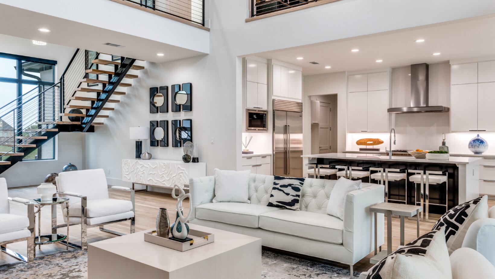 Bright open-concept luxury great room with layered ambient and pendant lighting by Landry Designs