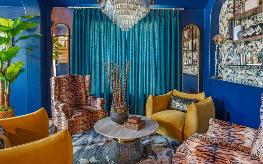 Custom home speakeasy by Landry Designs in Fort Worth, Texas — a midnight blue lounge with a botanical-wallpaper bar, crystal chandelier and velvet seating